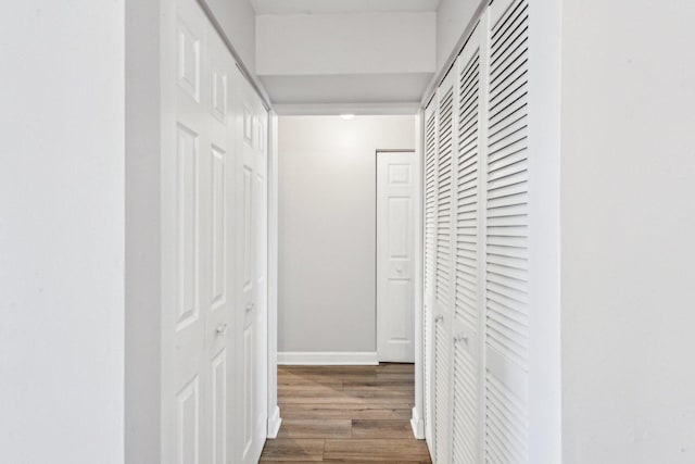 hall with baseboards and wood finished floors