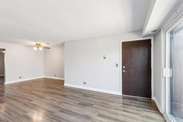 spare room featuring visible vents, a ceiling fan, light wood-style floors, and baseboards