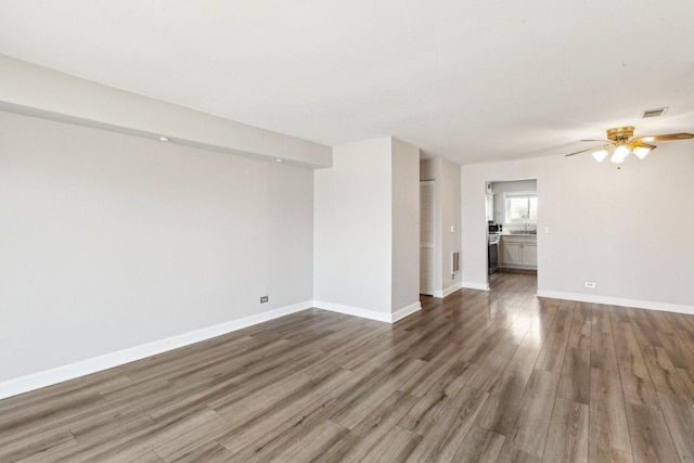 interior space with visible vents, baseboards, wood finished floors, a ceiling fan, and a sink