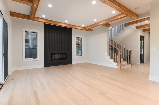 unfurnished living room with beamed ceiling, wood finished floors, recessed lighting, stairway, and baseboards