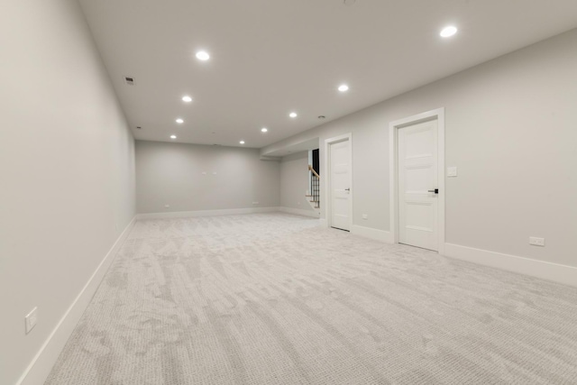 finished basement with visible vents, baseboards, recessed lighting, stairs, and light colored carpet