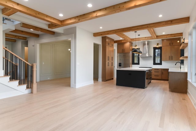 kitchen with wall chimney range hood, beamed ceiling, light wood-type flooring, stainless steel built in fridge, and light countertops