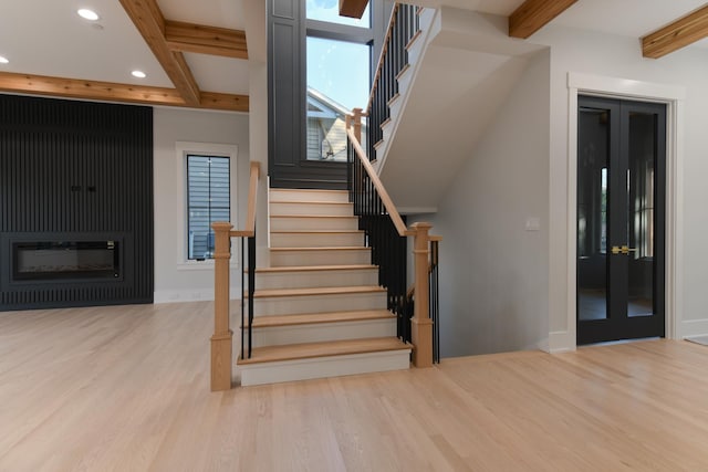 stairs with recessed lighting, beamed ceiling, baseboards, and wood finished floors