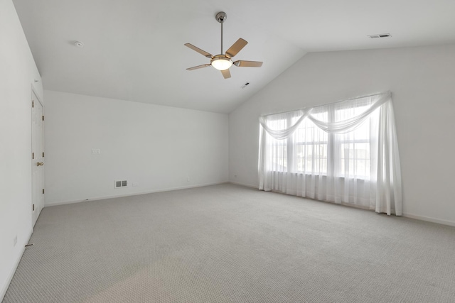 carpeted spare room with vaulted ceiling, a ceiling fan, visible vents, and baseboards