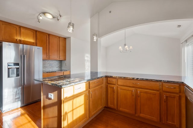 kitchen featuring dark stone countertops, dark wood-style floors, appliances with stainless steel finishes, a chandelier, and vaulted ceiling