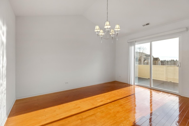 spare room featuring visible vents, baseboards, vaulted ceiling, wood finished floors, and a notable chandelier