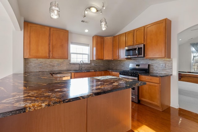 kitchen with visible vents, vaulted ceiling, a peninsula, stainless steel appliances, and a sink