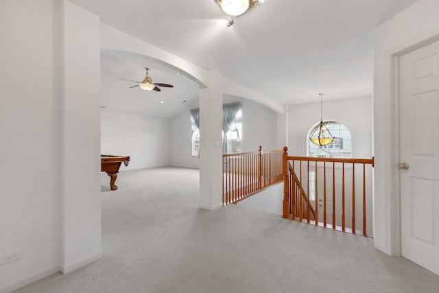 corridor featuring carpet floors, arched walkways, lofted ceiling, and an upstairs landing