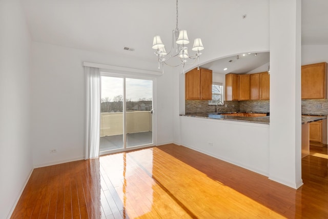 kitchen with a sink, light wood-style floors, a healthy amount of sunlight, and a chandelier