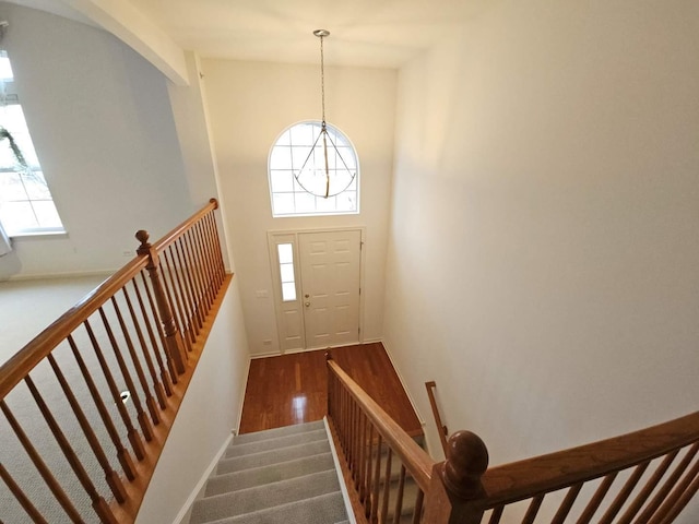 staircase featuring a wealth of natural light, baseboards, wood finished floors, and a towering ceiling