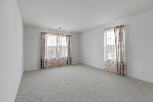 carpeted spare room featuring a wealth of natural light and baseboards