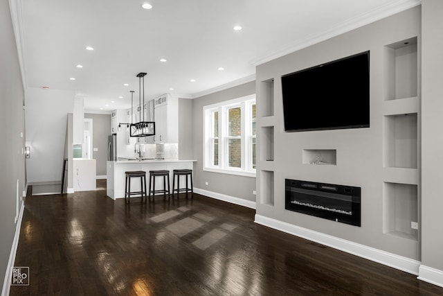 living room with dark wood-style floors, baseboards, recessed lighting, a glass covered fireplace, and crown molding