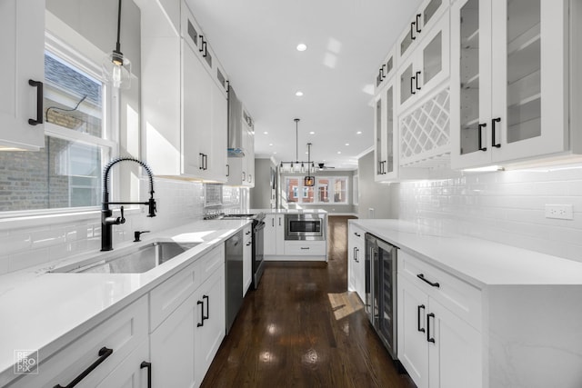 kitchen with beverage cooler, appliances with stainless steel finishes, a peninsula, hanging light fixtures, and a sink