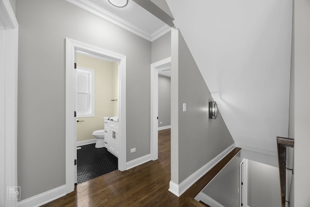 hallway featuring dark wood-style floors, crown molding, and baseboards