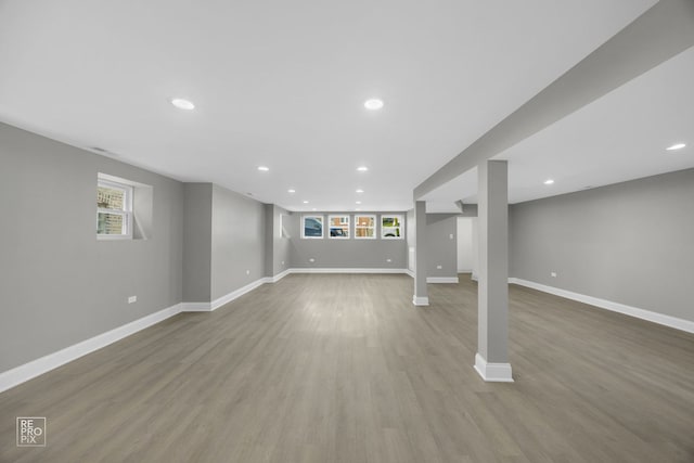 below grade area featuring recessed lighting, wood finished floors, baseboards, and a wealth of natural light