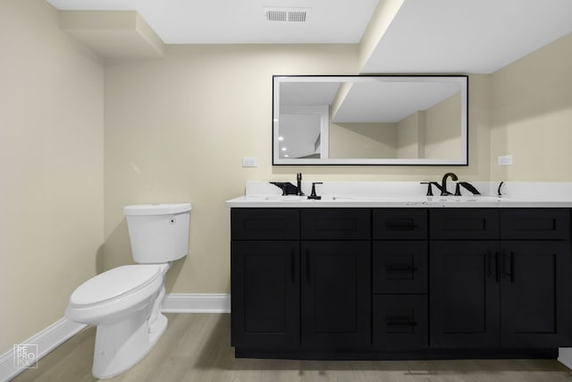 bathroom featuring a sink, visible vents, toilet, and wood finished floors