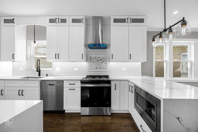 kitchen featuring light stone counters, dark wood finished floors, a sink, stainless steel appliances, and wall chimney exhaust hood