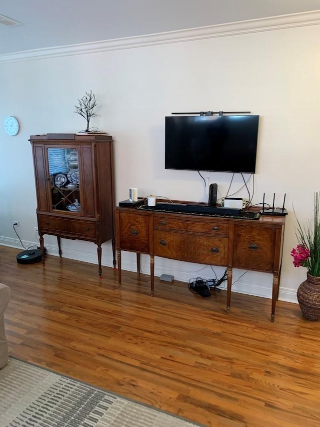 living room with visible vents, crown molding, baseboards, and wood finished floors