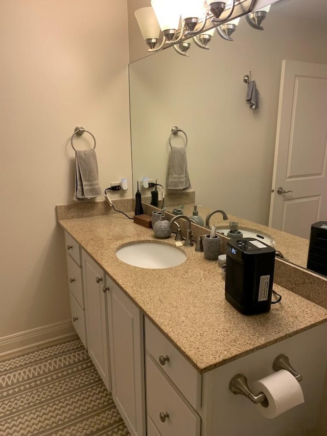 bathroom with a chandelier, vanity, and baseboards