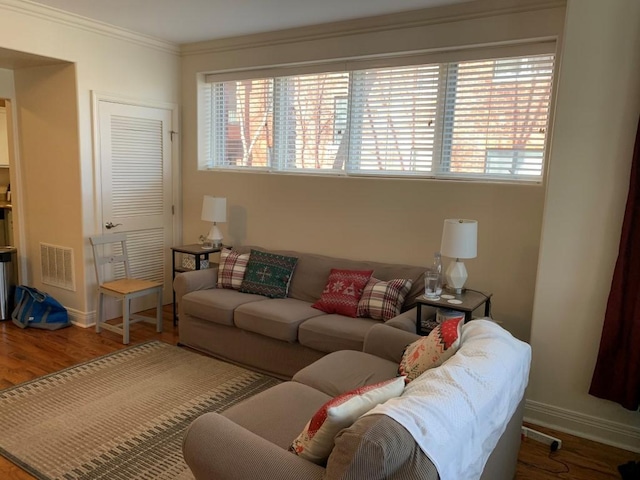 living area featuring visible vents, ornamental molding, baseboards, and wood finished floors