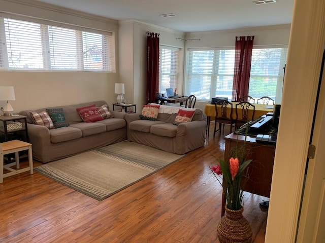 living room with visible vents, crown molding, and wood finished floors