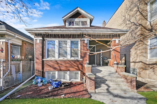 rear view of house featuring brick siding and fence