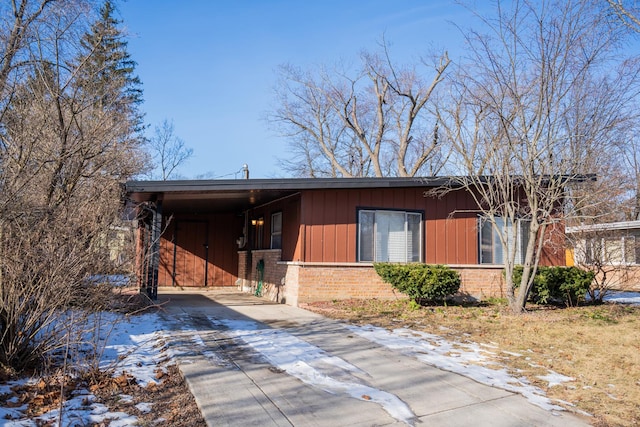 rear view of property featuring brick siding, an attached carport, and driveway