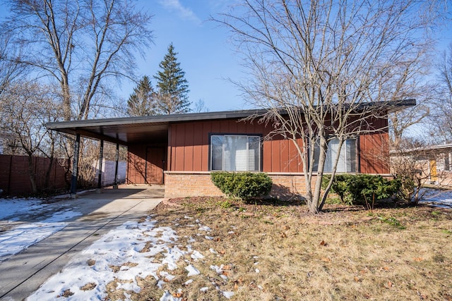 view of front of home featuring a carport, driveway, brick siding, and fence