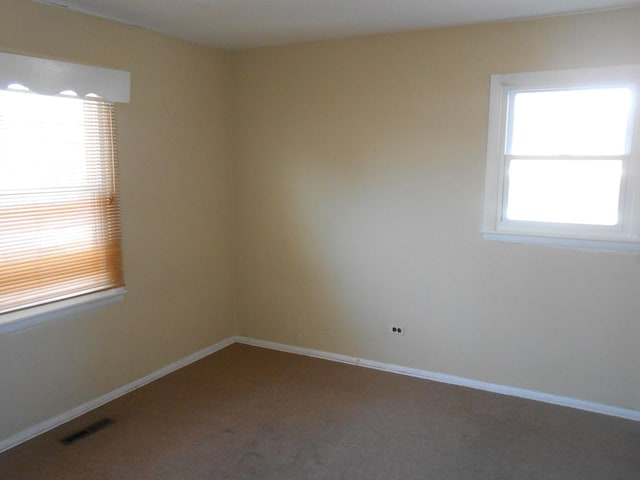 carpeted empty room featuring visible vents and baseboards