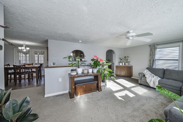 living room featuring a textured ceiling, plenty of natural light, arched walkways, and ceiling fan with notable chandelier