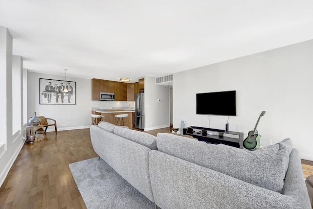 living area with visible vents, wood finished floors, and baseboards