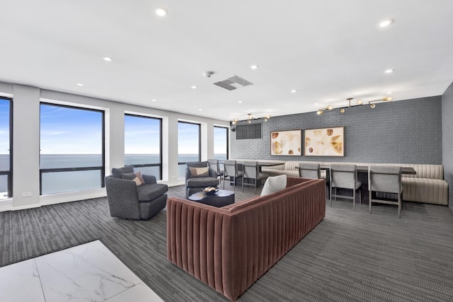 carpeted living room featuring visible vents, recessed lighting, brick wall, and track lighting