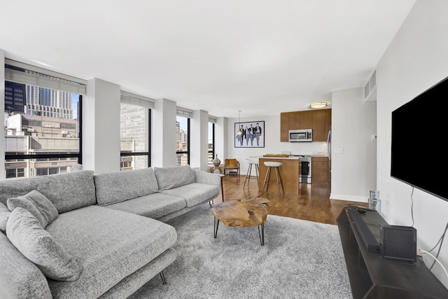 living area featuring visible vents, dark wood-style floors, and baseboards