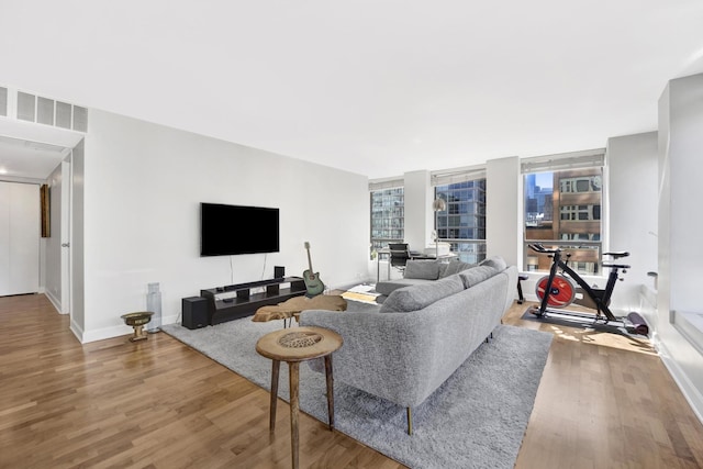 living room featuring visible vents, baseboards, and wood finished floors