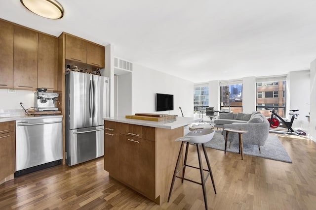 kitchen featuring open floor plan, stainless steel appliances, dark wood-type flooring, and visible vents