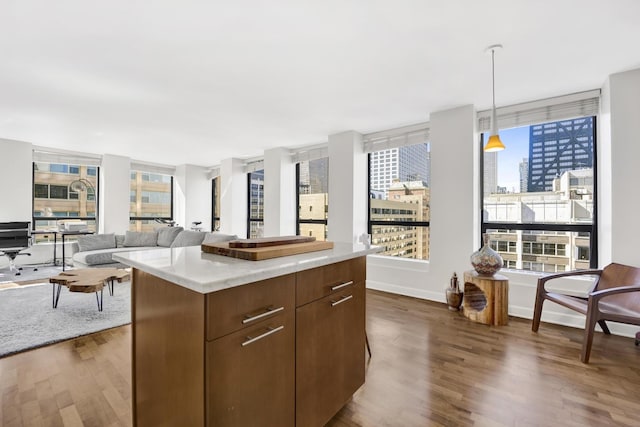 kitchen with a kitchen island, baseboards, dark wood finished floors, light countertops, and hanging light fixtures