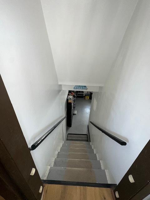 stairway with wood finished floors and vaulted ceiling