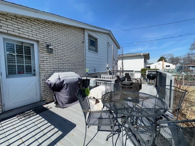 deck with outdoor dining area and a grill