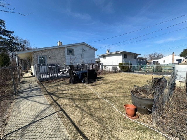 back of house with a lawn, fence, brick siding, and a chimney