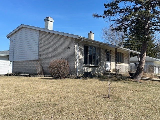 exterior space with a lawn, brick siding, and a chimney