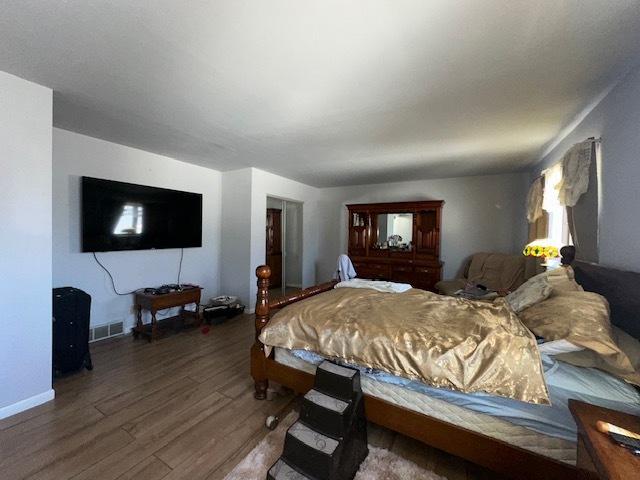 bedroom with visible vents, baseboards, and wood finished floors