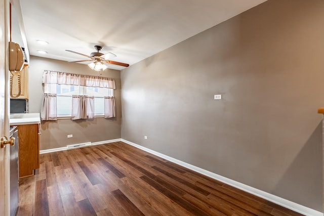 spare room with visible vents, baseboards, dark wood-style floors, and ceiling fan