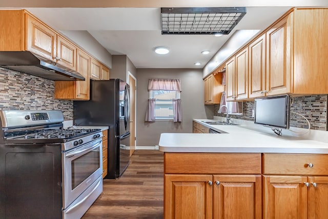 kitchen featuring under cabinet range hood, a sink, dark wood-style floors, baseboards, and stainless steel gas range