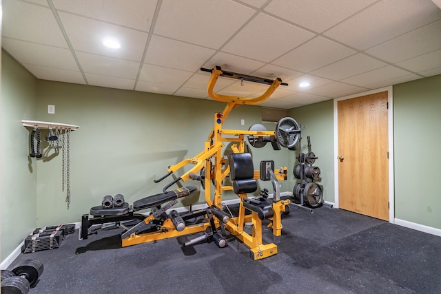 exercise area featuring recessed lighting, a paneled ceiling, and baseboards