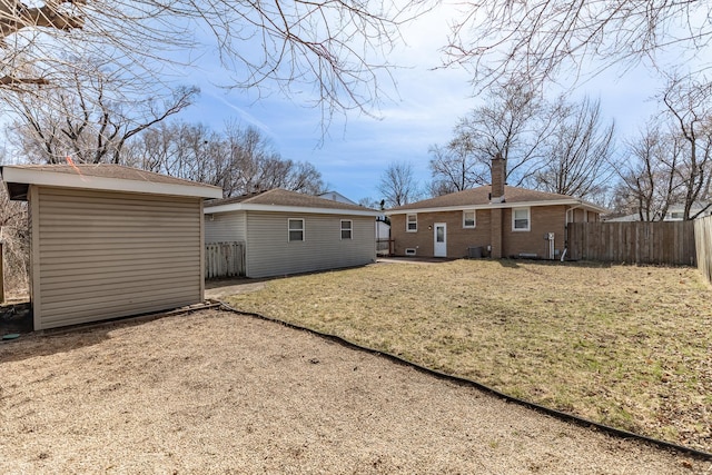 rear view of property with an outbuilding, a yard, and a fenced backyard