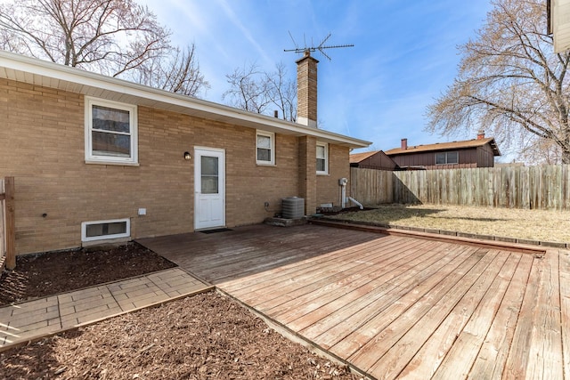 back of house featuring cooling unit, fence, a chimney, a deck, and brick siding