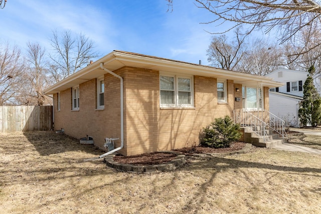 view of home's exterior featuring brick siding and fence