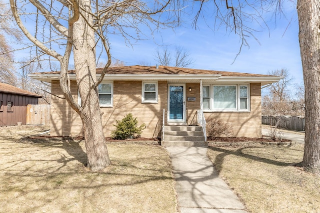 view of front of home with brick siding, entry steps, and fence