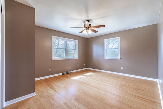 spare room with a wealth of natural light, visible vents, light wood-style floors, and a ceiling fan