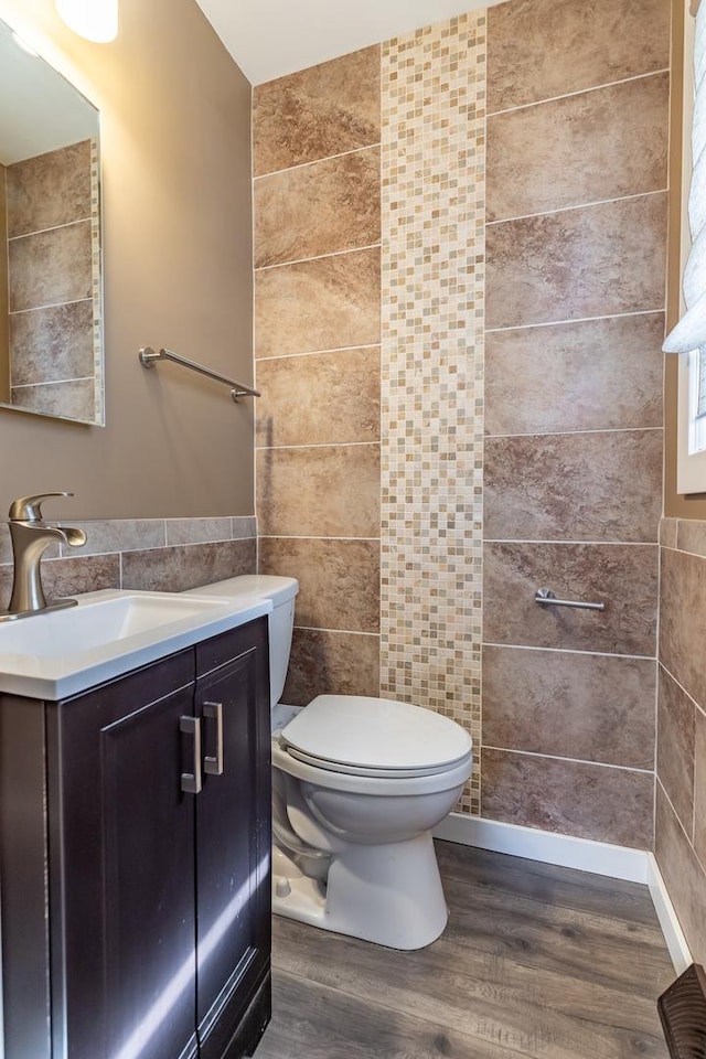 bathroom featuring vanity, tile walls, toilet, and wood finished floors